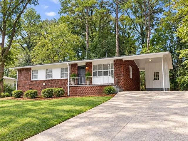 Brick exterior with white trim, covered carport, and a concrete driveway