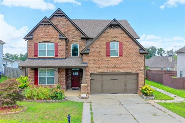 Brick exterior with gabled roof lines, covered front porch, arched window accents, and an attached two-car garage