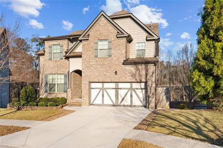 Craftsman-style home with driveway, brick siding, a garage, and a front lawn