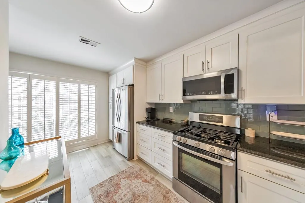 KITCHEN FEATURING STAINLESS STEEL APPLIANCES, WHITE CABINETS AND GRANITE COUNTERTOPS!