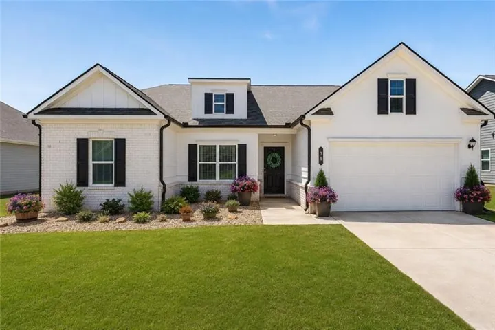 White brick and siding exterior with black shutters, attached two-car garage, concrete driveway, and a front walk leading to the entrance