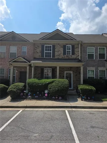Brick facade with a covered porch entry, dark shutters, and a gabled roofline