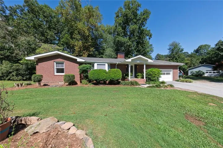 Brick exterior with a covered entry, attached garage, and a separate detached garage