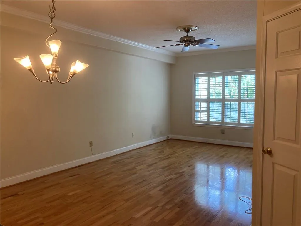 Spare room with ornamental molding, a chandelier, wood finished floors, ceiling fan, and a textured ceiling