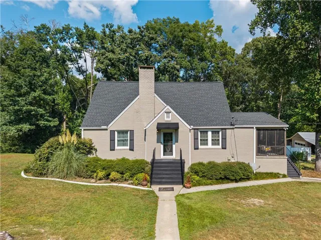 Gray brick exterior with a dark shingle roof, complemented by a screened porch and black exterior shutters