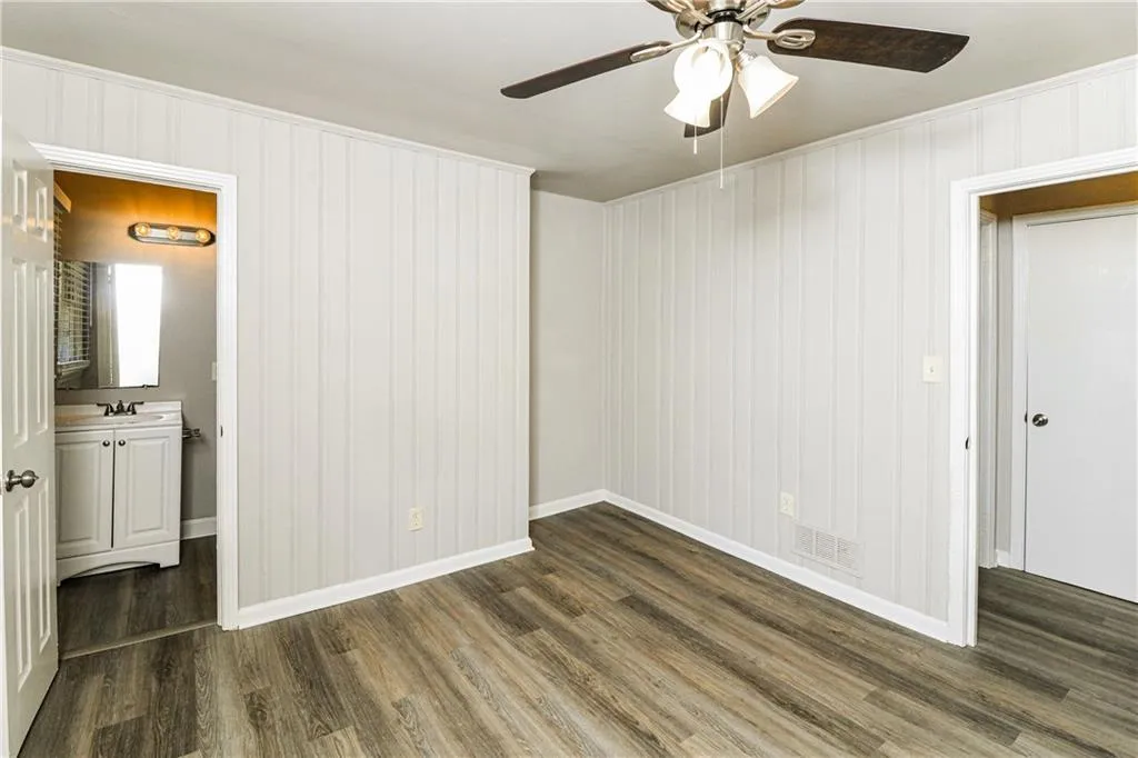 Spare room with dark wood-type flooring, a ceiling fan, and wooden walls