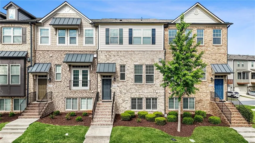Brick-front townhome featuring a multi-level facade, prominent gable details, and a blue entry door