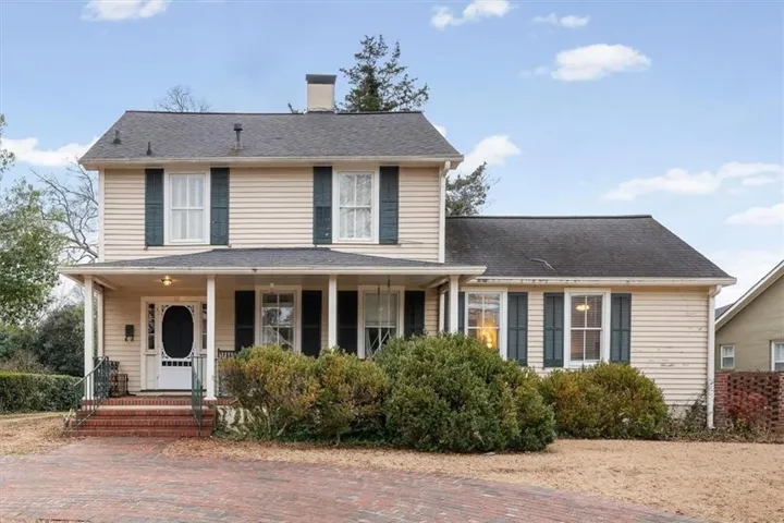 Traditional two-story residence featuring light-colored siding and a covered front porch