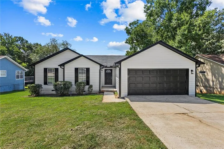 White exterior siding with dark trim, black panel garage door, black window shutters, and a concrete driveway
