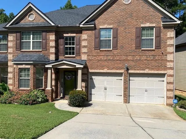 Brick facade with stone accents, two-car garage, covered entry, and gabled roofline