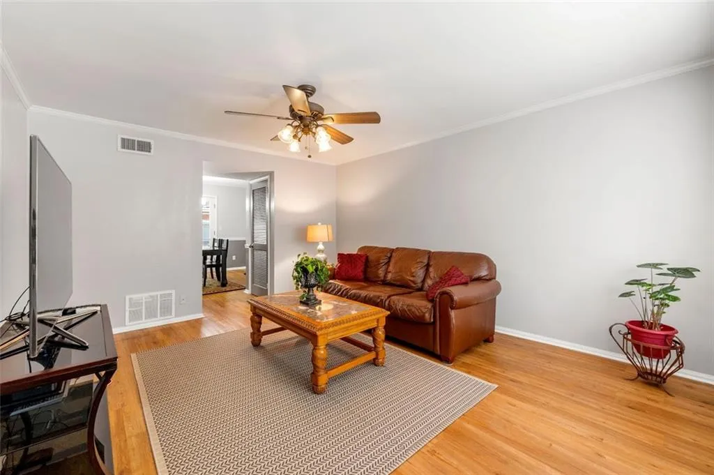 Living room featuring ornamental molding, hardwood / wood-style flooring, and ceiling fan Living room featuring ornamental molding, hardwood / wood-style flooring, and ceiling fan