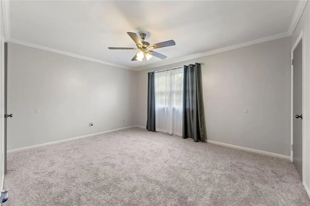 Carpeted spare room with ornamental molding and ceiling fan Carpeted spare room with ornamental molding and ceiling fan