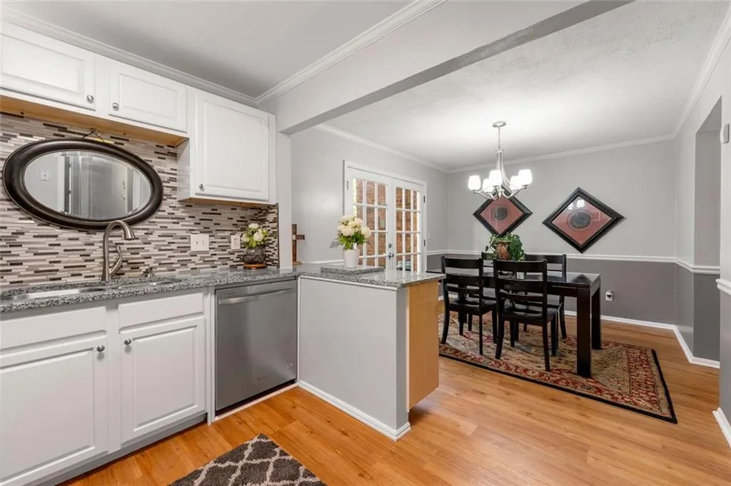 Kitchen featuring white cabinetry, decorative backsplash, dishwasher, light stone countertops, and light hardwood / wood-style floors Kitchen featuring white cabinetry, decorative backsplash, dishwasher, light stone countertops, and light hardwood / wood-style floors