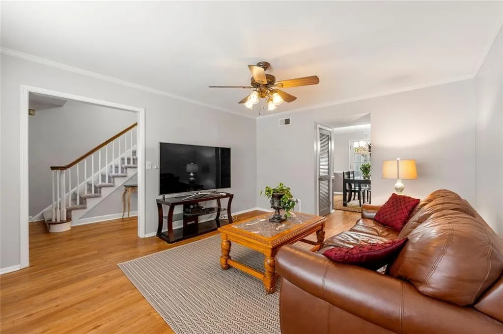 Living room with ornamental molding, light hardwood / wood-style flooring, and ceiling fan with notable chandelier Living room with ornamental molding, light hardwood / wood-style flooring, and ceiling fan with notable chandelier