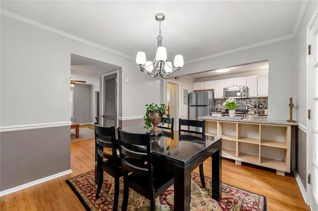 Dining space featuring ornamental molding, ceiling fan with notable chandelier, and light wood-type flooring Dining space featuring ornamental molding, ceiling fan with notable chandelier, and light wood-type flooring