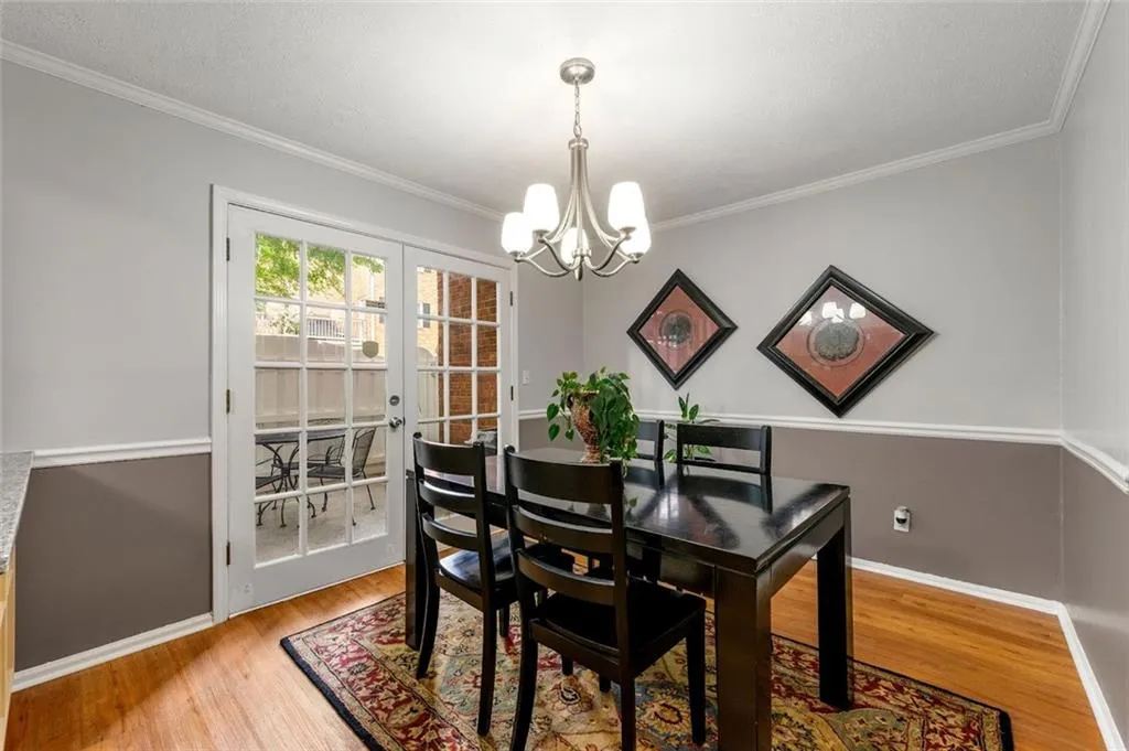 Dining space featuring a notable chandelier, french doors, light wood-type flooring, and ornamental molding Dining space featuring a notable chandelier, french doors, light wood-type flooring, and ornamental molding