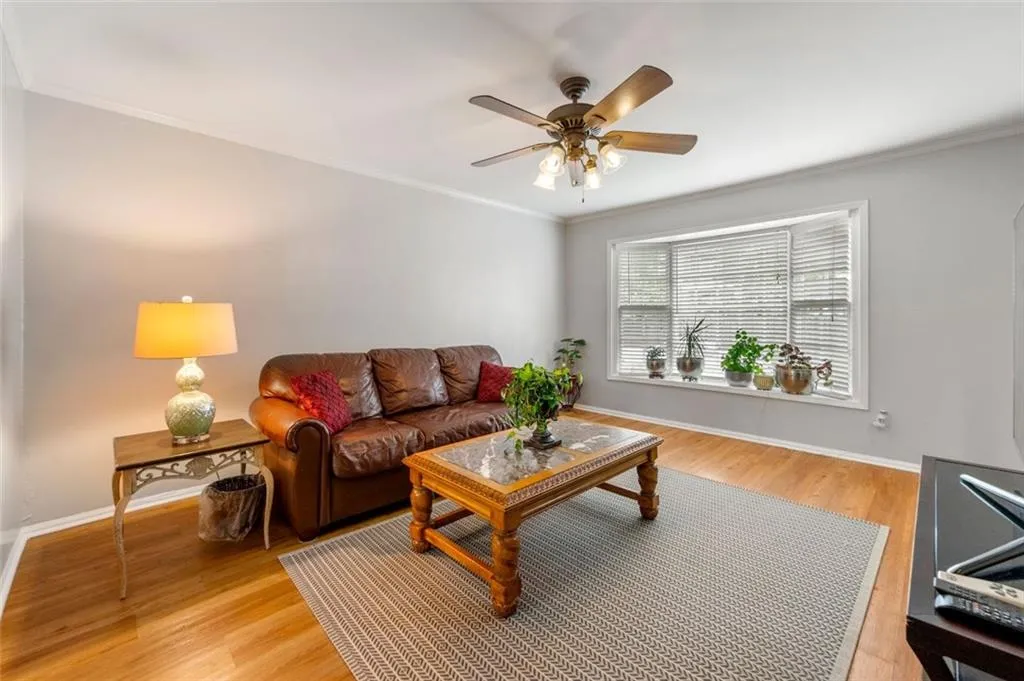 Living room with ceiling fan, light wood-type flooring, and crown molding Living room with ceiling fan, light wood-type flooring, and crown molding