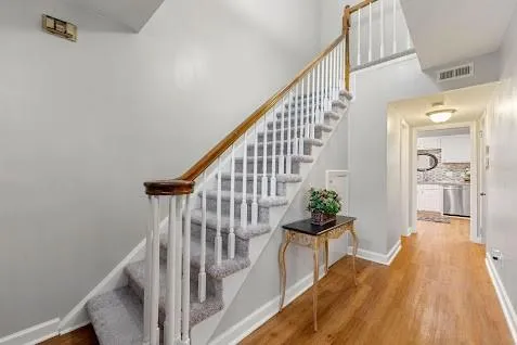 Stairway featuring light wood-type flooring and a towering ceiling Stairway featuring light wood-type flooring and a towering ceiling
