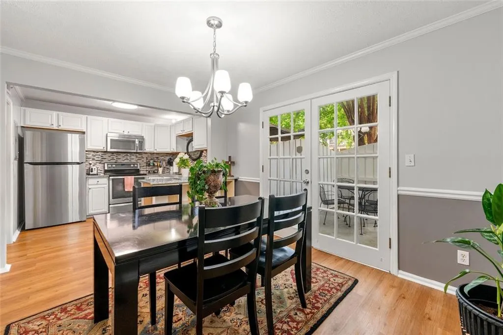 Dining space featuring light hardwood / wood-style floors, crown molding, french doors, and an inviting chandelier Dining space featuring light hardwood / wood-style floors, crown molding, french doors, and an inviting chandelier