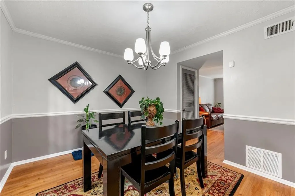 Dining space featuring light hardwood / wood-style floors, a notable chandelier, and ornamental molding Dining space featuring light hardwood / wood-style floors, a notable chandelier, and ornamental molding