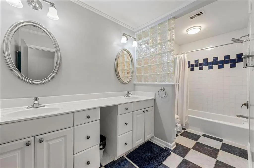 Full bathroom with vanity, shower / bathtub combination with curtain, tile patterned floors, ornamental molding, and toilet Full bathroom with vanity, shower / bathtub combination with curtain, tile patterned floors, ornamental molding, and toilet