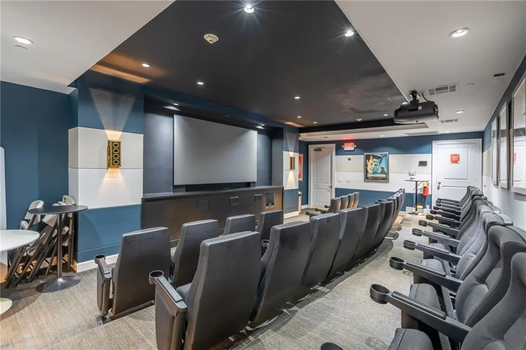 Carpeted cinema room featuring a tray ceiling and recessed lighting