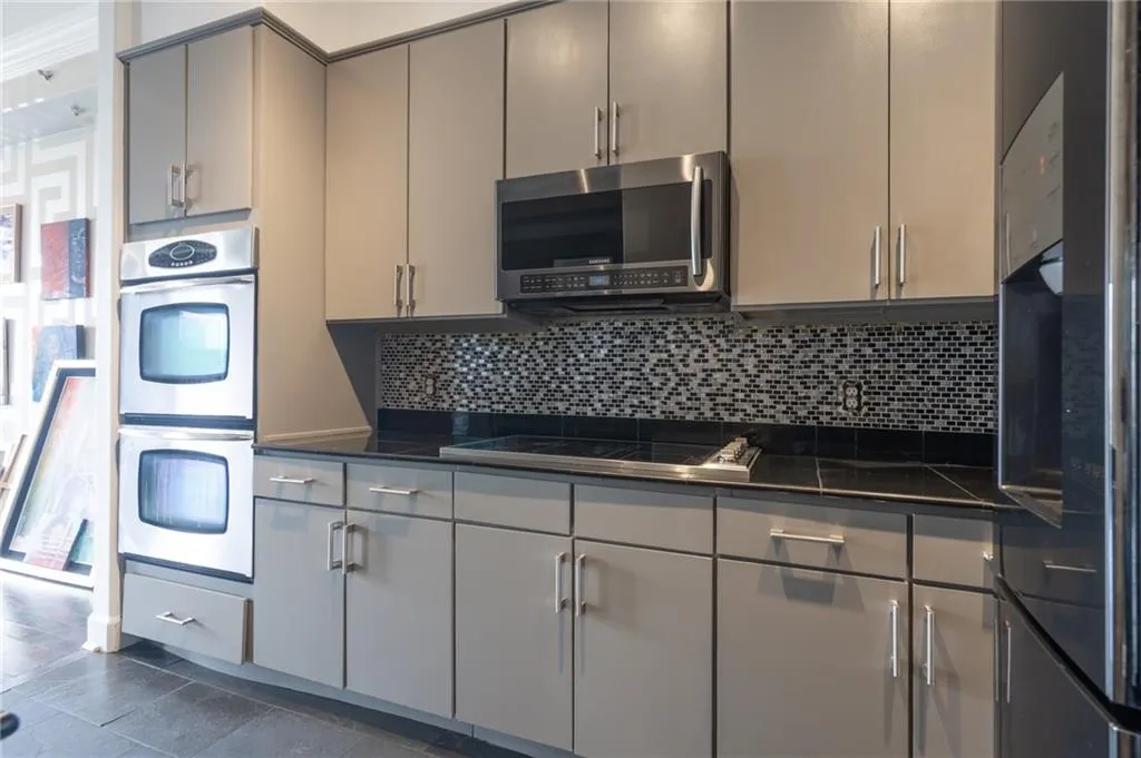 Kitchen featuring dark countertops, gray cabinets, stainless steel appliances, and backsplash
