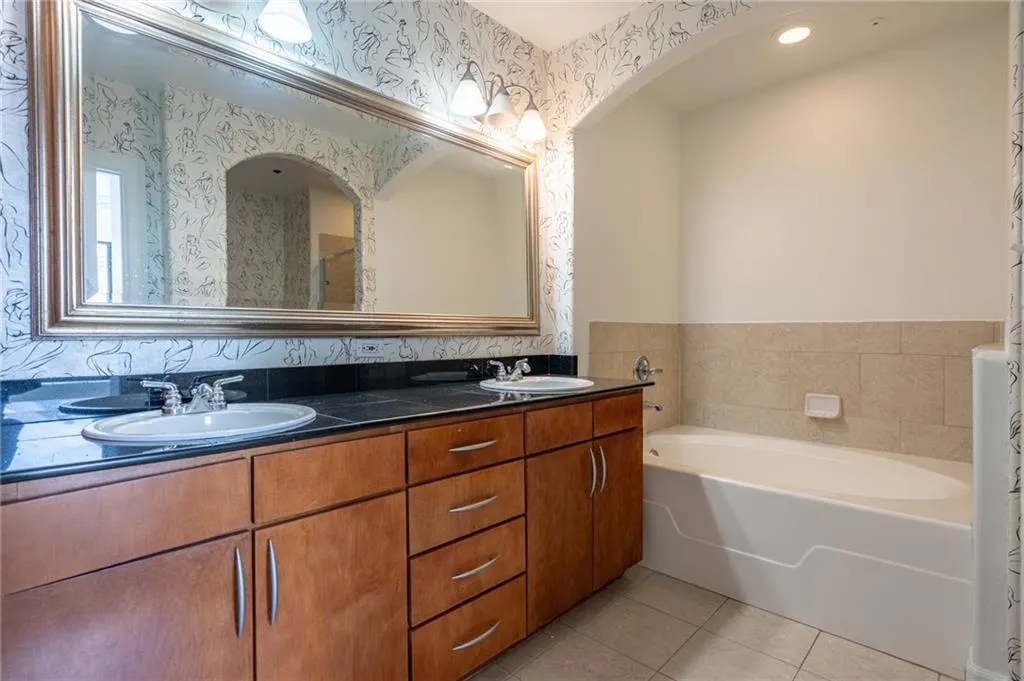 Full bath featuring tile patterned floors, double vanity, and a garden tub