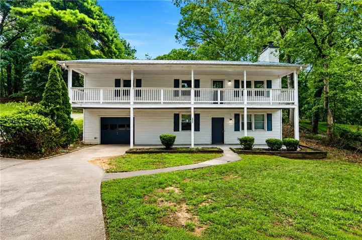 Two-story white exterior with a covered upper balcony, ground-level entry, and an integrated garage