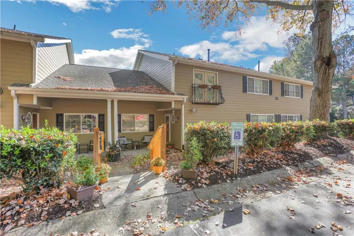 Two-story exterior with a covered porch, an upper-level balcony, and mature landscaping