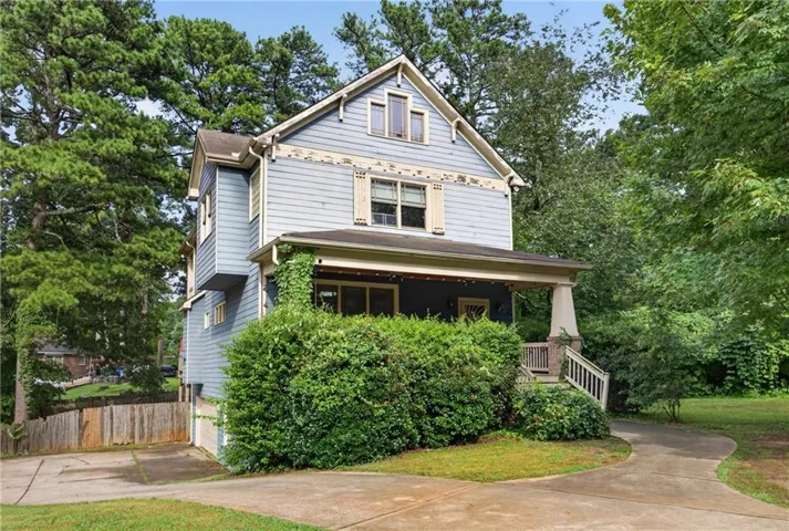 Two-story residence featuring light blue siding, a front porch with square columns, and a gabled roofline