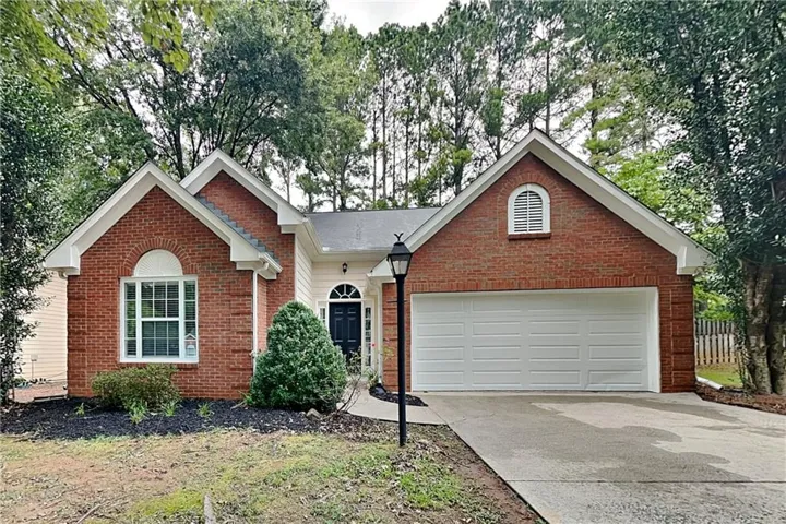 Brick exterior with arched window accents, attached two-car garage, and established landscaping