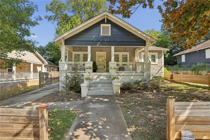 Craftsman-style exterior with a gabled roof, covered front porch, concrete walkway, and a partial wooden fence