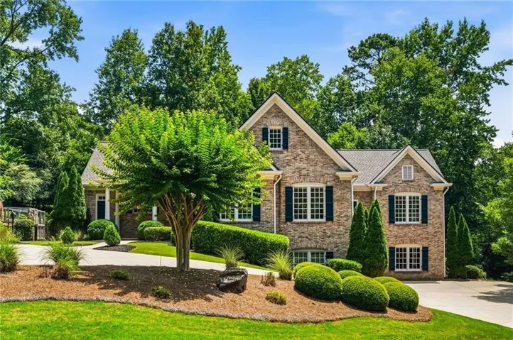 Traditional brick exterior featuring a multi-gabled roofline, dark shutters, and white-framed windows