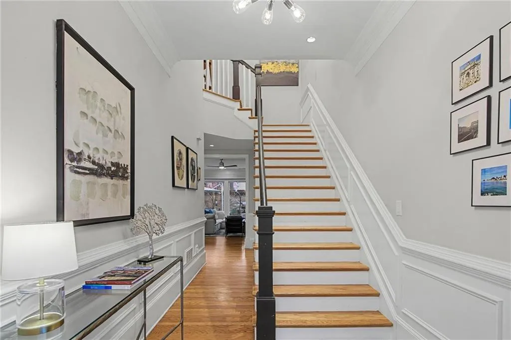 Stairs with crown molding, a decorative wall, a wainscoted wall, and wood finished floors