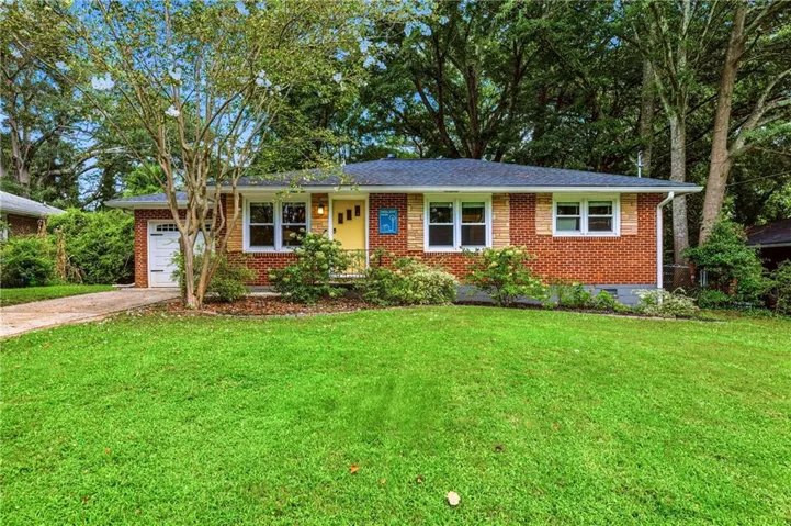 Brick and wood-sided exterior with a shingled roof, a garage with a paneled door, and a vibrant yellow front door