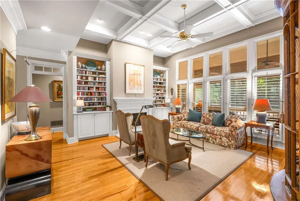 Expansive living room has floor to ceiling windows, a gas fireplace with gas logs, built in bookshelves, and coffered 11 foot ceilings