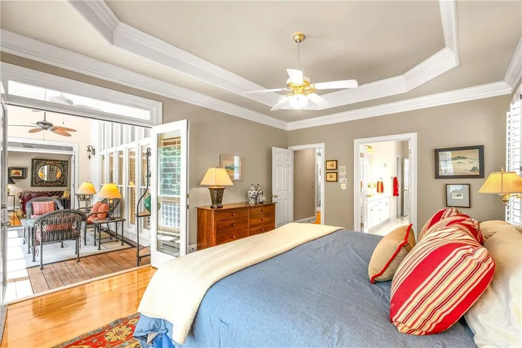 Main floor primary bedroom suite is oversized with a tray ceiling, two walk-in closets, and another set of French doors that open directly to the screen porch