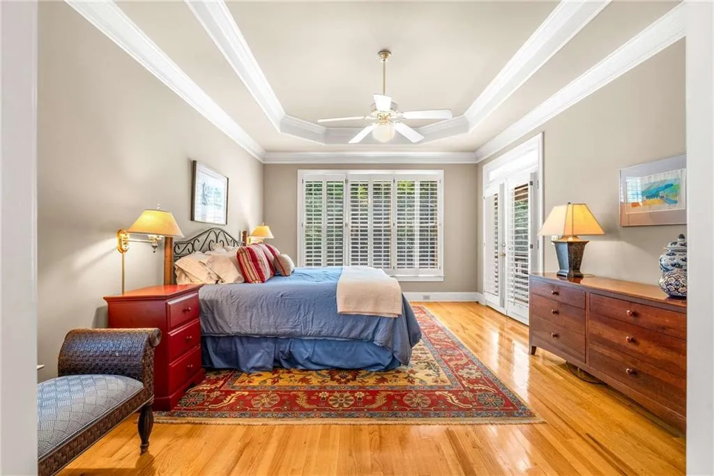 Main floor primary bedroom suite is oversized with a tray ceiling, two walk-in closets, and another set of French doors that open directly to the screen porch