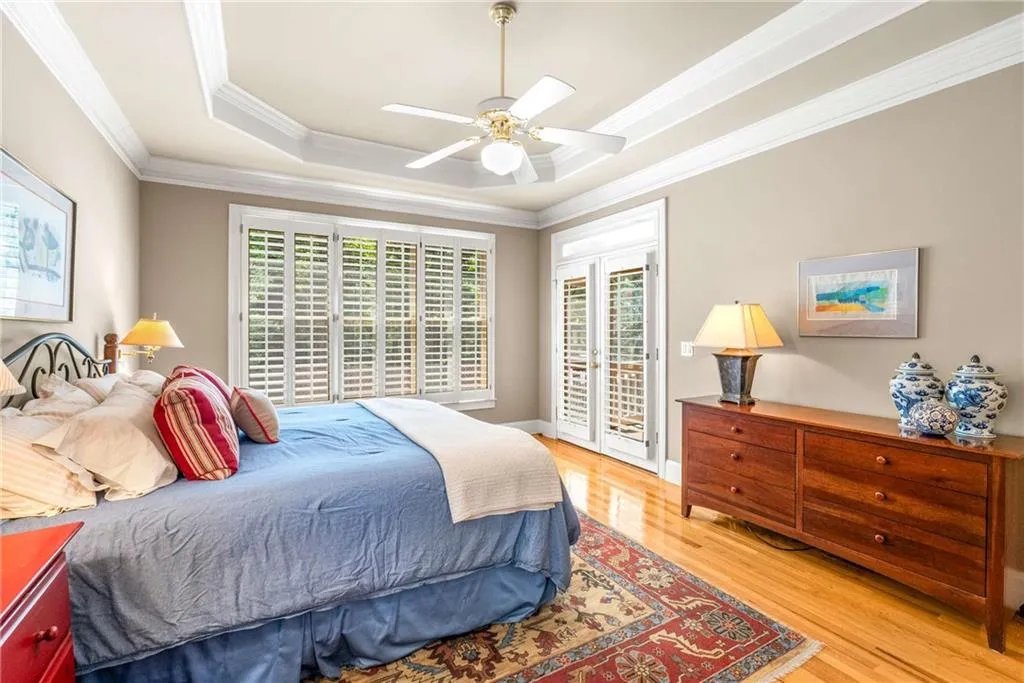 Main floor primary bedroom suite is oversized with a tray ceiling, two walk-in closets, and another set of French doors that open directly to the screen porch