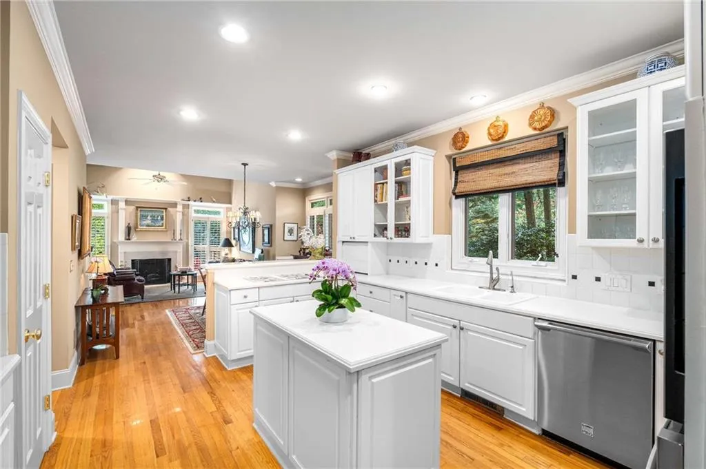 Kitchen features white cabinets and white countertops, a peninsula and an island, gas cooktop, stainless steel wall oven,  built-in microwave, side by side refrigerator, and multiple pantry closets