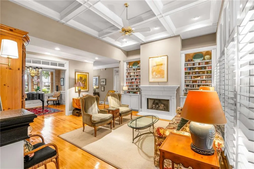 Expansive living room has floor to ceiling windows, a gas fireplace with gas logs, built in bookshelves, and coffered 11 foot ceilings
