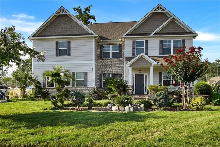 Elegant two-story colonial featuring a brick and vinyl exterior with peaked rooflines and architectural detail