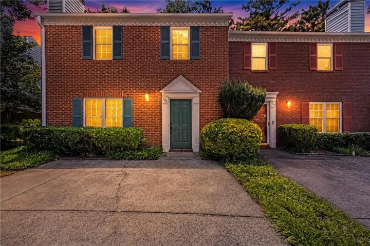 Traditional brick townhouse with a teal paneled entry door, white pediment door surround, and contrasting window shutters