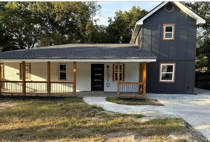 View of front facade with board and batten siding, a porch, brick siding, and a shingled roof