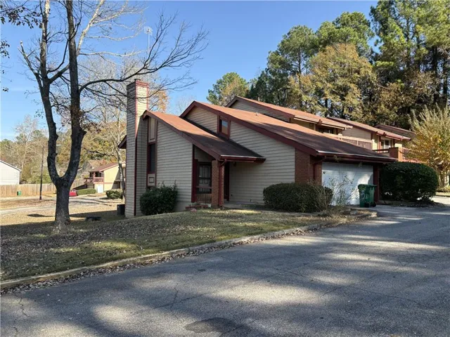 View of front of home featuring a chimney, brick siding, driveway, and a front yard