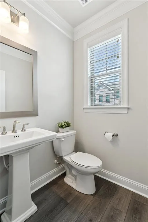 Bathroom with ornamental molding and wood finished floors