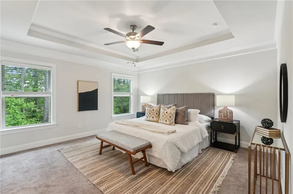 Carpeted bedroom featuring crown molding, a raised ceiling, and a ceiling fan