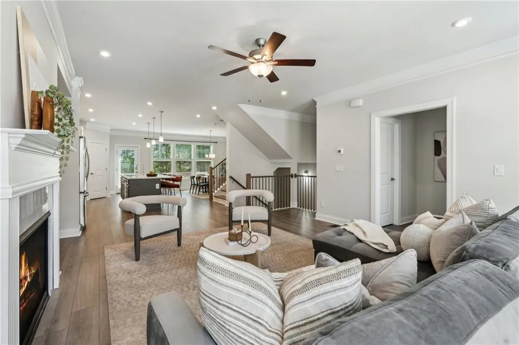 Living room with ornamental molding, a fireplace, ceiling fan, dark wood finished floors, and recessed lighting