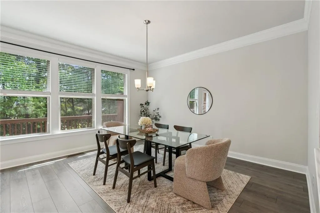 Dining space with dark wood-style floors, a chandelier, and ornamental molding
